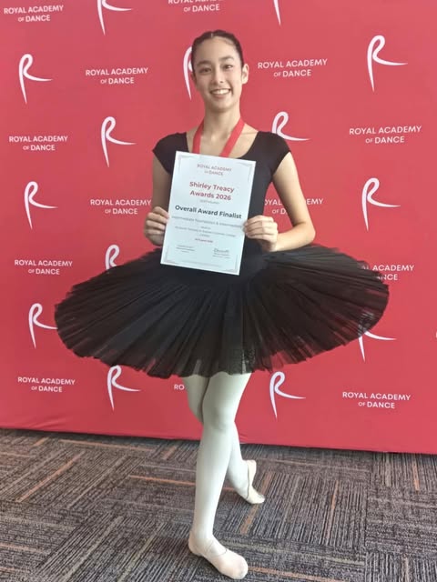 JMDS student in a black tutu holding her RAD Shirley Teacy Awards finalist certificate