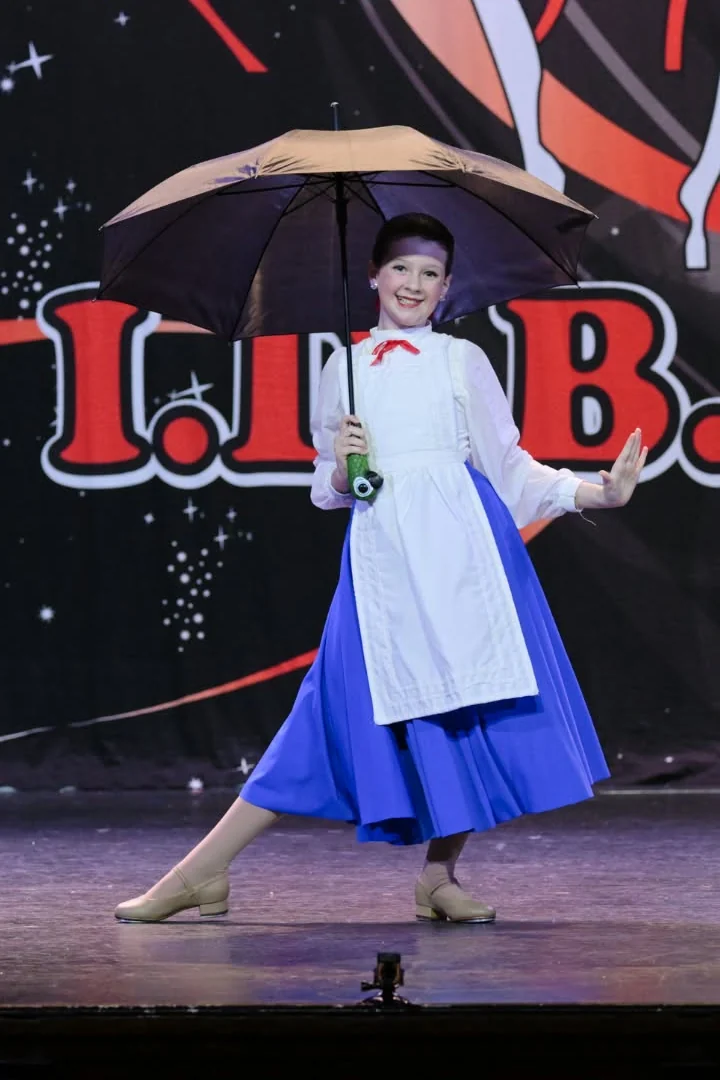 JMDS soloist on stage holding an umbrella
